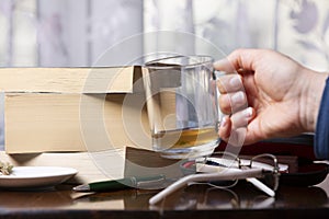 Books, pen, drink and glasses over a wood table close-up