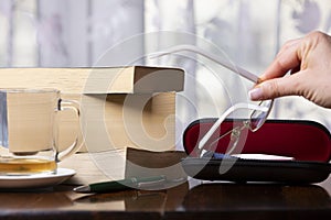 Books, pen, drink and glasses over a wood table close-up