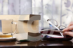 Books, pen, drink and glasses over a wood table close-up