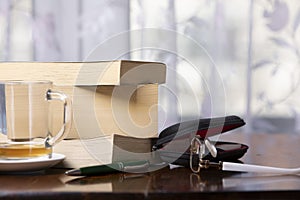 Books, pen, drink and glasses over a wood table close-up