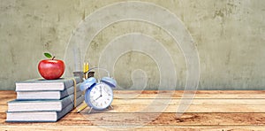 Books with red apple and blue clock