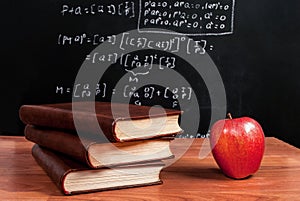 Books and red apple on a wooden table in math class in the classroom