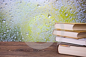 Books on an retro wooden table on a rainy day window background