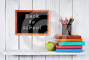 Books and school tools on wooden shelf.