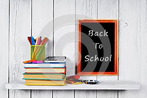 Books and school tools on wooden shelf.