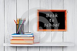 Books and school tools on wooden shelf.