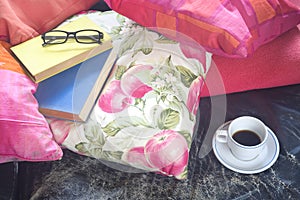 Books on a sofa with cup of coffee and specs