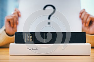 Books, stack and closeup on desk for faith, Abrahamic religion and question mark on poster for study in home. Person