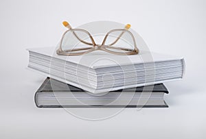 Books stack with eyeglasses. Education concept. Encyclopedia, bible, code or classics novel on grey background.