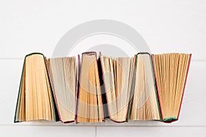 Books stand vertically on shelves, open, roots green, red and brown.