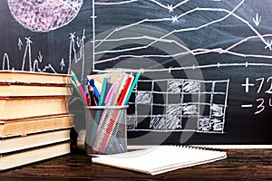 Books on the table against the background of a chalkboard on which are drawn graphs and charts of growth and decline. Business