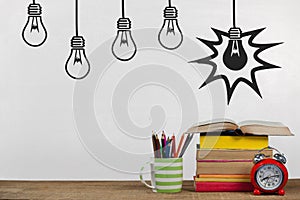 Books on the table against white blackboard with bulb graphics