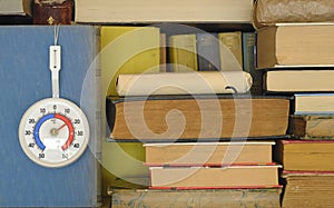 Books and thermometer showing low temperature in a library due to shortage of heating gas and oil