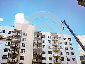 boom of a crane against the background of a high-rise residential building made of monolithic reinforced concrete