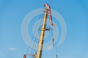 The boom of a large port cranes against a blue sky background,