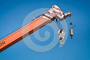 Boom Lifting Crane With Cable Hook Against Blue Sky Background. Hydraulic Lifting Mover of Mobile Machine During Operation in