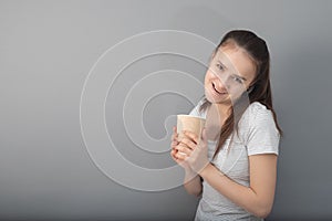 A boost of energy in a glass of invigorating coffee. Young woman drinks hot drink on gray background