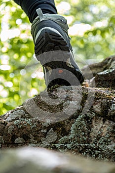 Boot of hiker on forest trail. Traveler feet are stepping on the rock . Adventure and hiking concept outdoor. Hipster lifestyle