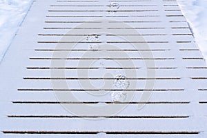 Boot prints left in the snow on a wooden path