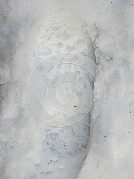 A boot tread imprint left in winter snow.