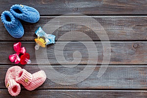 Booties for newborn boy and girl with dummy on wooden background top view mock up