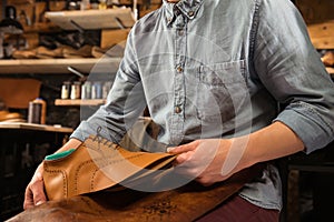 Bootmaker sitting in workshop making shoes