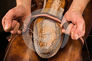 Bootmaker sitting in workshop making shoes