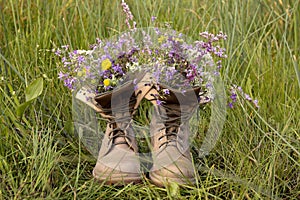 Boots with beautiful wild flowers on grass