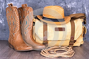 boots, hat and a canvas bag against a gray wall. Adventure and travel concept