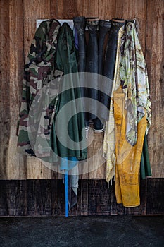 Boots and oilskins hanging on a coat rack on a wooden wall