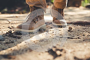Boots of traveler step on dry ground in forest
