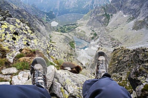 Boots of a woman sitting on the edge of a cliff in