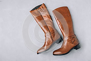 Boots. Women's brown leather high long boots on gray background.