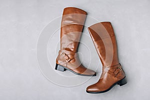 Boots. Women's brown leather high long boots on gray background.