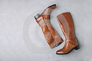 Boots. Women's brown leather high long boots on gray background.