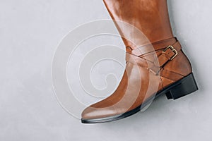 Boots. Women's brown leather high long boots on gray background. Top view