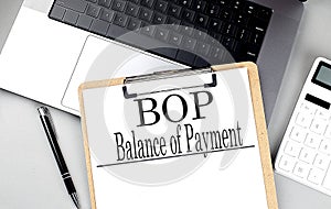 BOP- BALANCE OF PAYMENT word on clipboard on laptop with calculator and pen