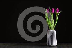 boquet of tulip on a black background standing in a grey vase