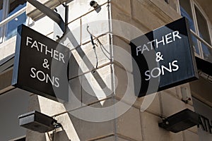 father & sons logo brand and text sign on wall facade shop entrance in city