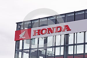 Honda motorcycle wing logo and red text sign front of dealership store motorbike
