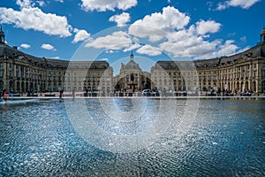 Tourists visiting the Place de la Bourse seen from the boulevard with in front the mirror fountain: Mirroir d`eau