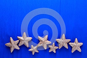 Border from big and small golden decorative stars on blue  paper textured background.