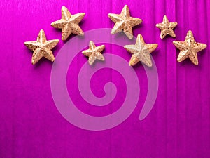 Border with big and small golden decorative stars on bright pink paper textured background.