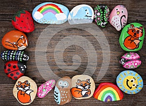 Border of Colorful Cartoon Hand Painted Animal Rocks on Wood Background photo