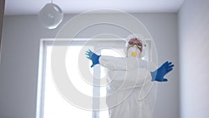 Border control, quarantine, pandemic threat, coronavirus. A man in white in a protective suit shows a stop sign with his