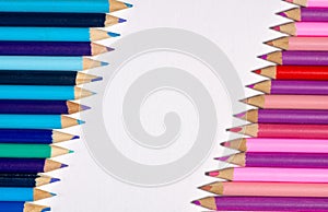 Border / edge of colored pencils with blue/purple on one side and pink/purple on the opposite with white space in-between.