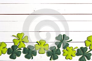 Border of felt four-leaf clover on white wooden background. Luck