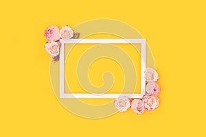 Border frame made of pink rose flowers on a yellow background.