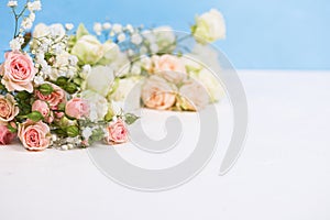 Border from fresh white gypsofila and white rose flowers against blue textured background photo