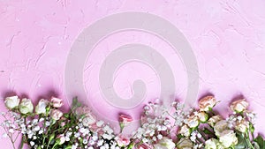 Border from fresh white gypsofila and white rose flowers on pink textured background photo
